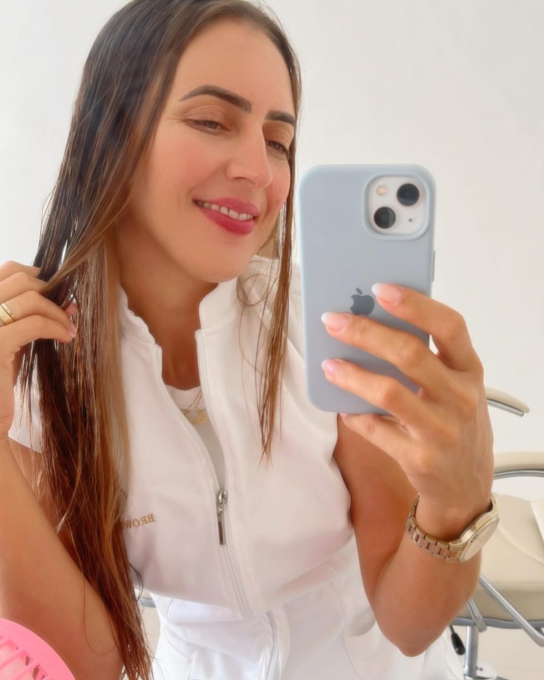 Cidinha de jaleco branco, sorrindo, em foto no espelho do estúdio